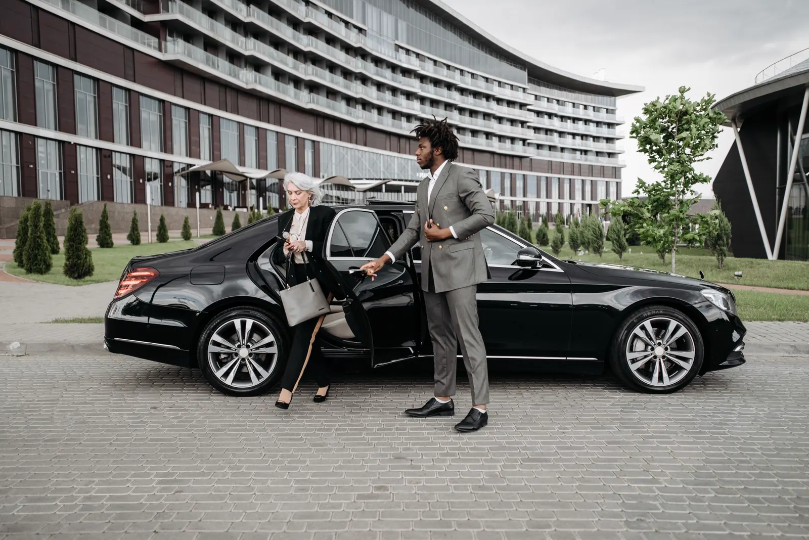 Chauffeur helping a business traveler out of a black sedan